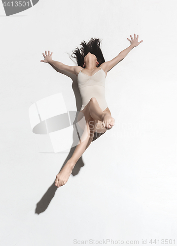 Image of Young beautiful dancer in beige dress dancing on gray background