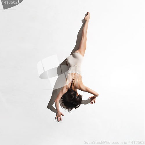 Image of Young beautiful dancer in beige dress dancing on gray background