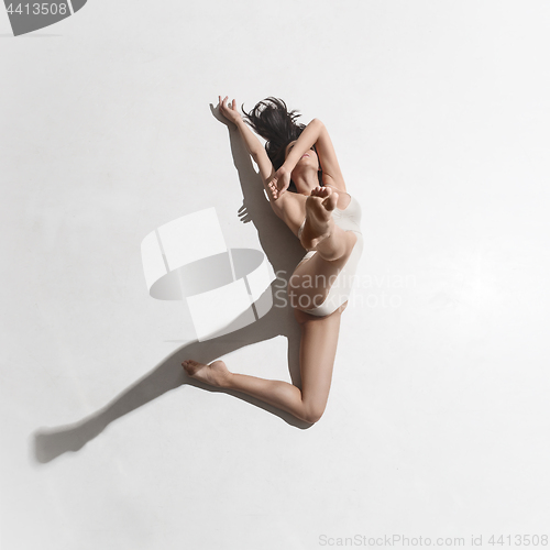 Image of Young beautiful dancer in beige dress dancing on gray background