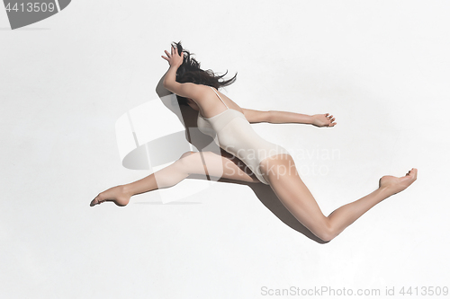 Image of Young beautiful dancer in beige dress dancing on gray background