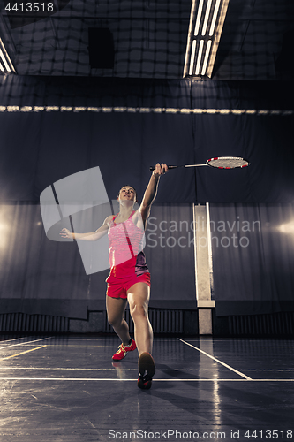 Image of Young woman playing badminton at gym