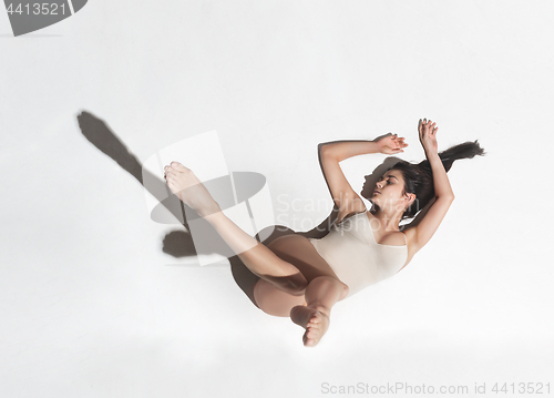 Image of Young beautiful dancer in beige dress dancing on gray background