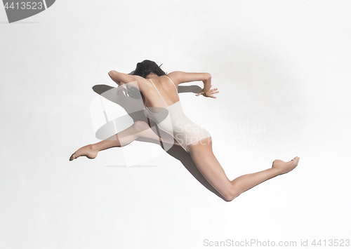 Image of Young beautiful dancer in beige dress dancing on gray background