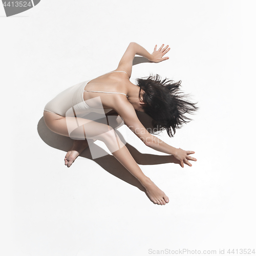 Image of Young beautiful dancer in beige dress dancing on gray background