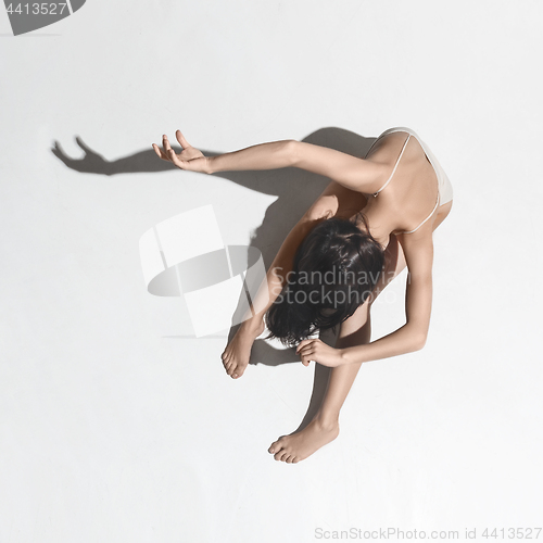 Image of Young beautiful dancer in beige dress dancing on gray background