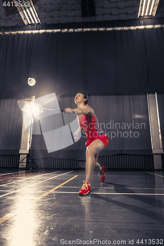 Image of Young woman playing badminton at gym