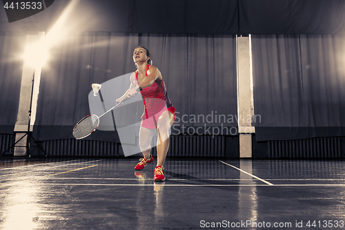 Image of Young woman playing badminton at gym