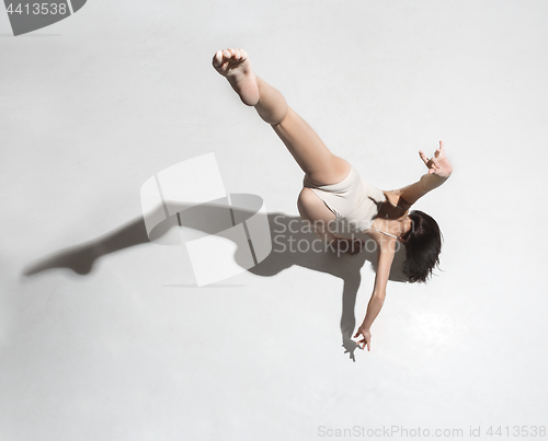 Image of Young beautiful dancer in beige dress dancing on gray background