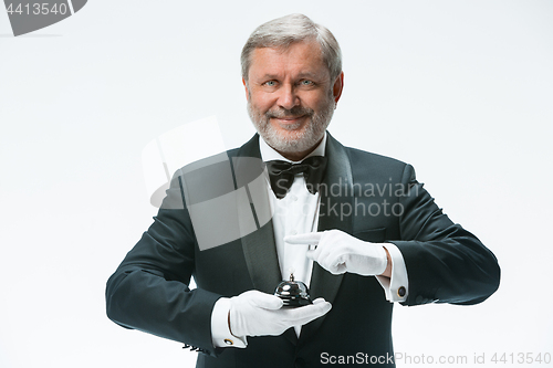 Image of Senior waiter holding bell