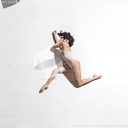 Image of Young beautiful dancer in beige dress dancing on gray background