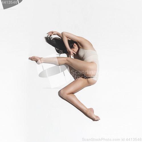 Image of Young beautiful dancer in beige dress dancing on gray background