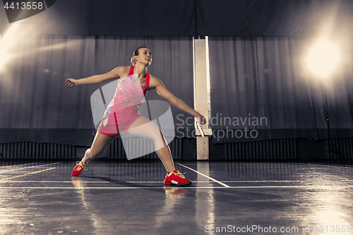 Image of Young woman playing badminton at gym