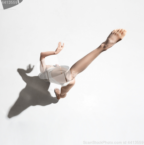 Image of Young beautiful dancer in beige dress dancing on gray background