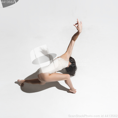 Image of Young beautiful dancer in beige dress dancing on gray background