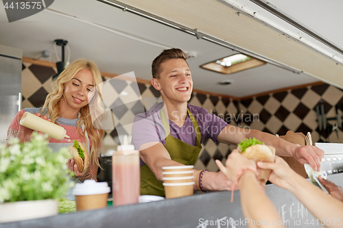 Image of happy sellers serving customers at food truck