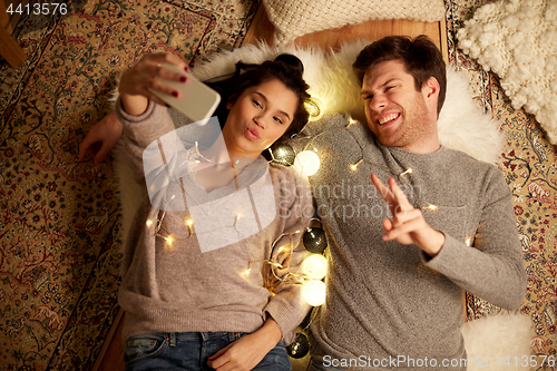 Image of couple lying on floor and making selfie at home