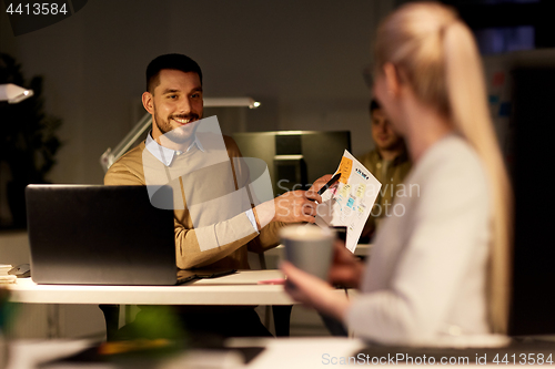 Image of colleagues discussing project at night office