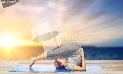 Image of woman making yoga in plow pose on mat