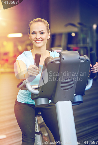 Image of smiling woman exercising on exercise bike in gym