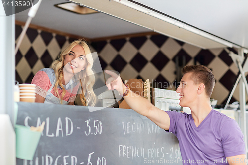 Image of saleswoman at food truck serving male customer