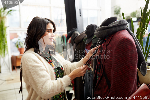 Image of happy woman choosing clothes at clothing store