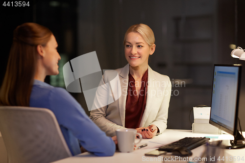 Image of happy businesswomen talking late at night office