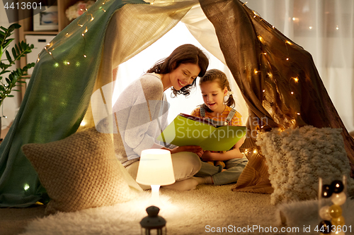 Image of happy family reading book in kids tent at home