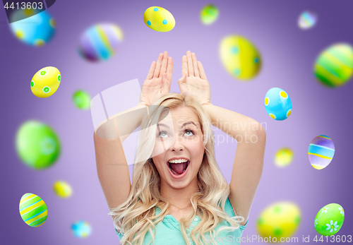 Image of happy woman making bunny ears over easter eggs