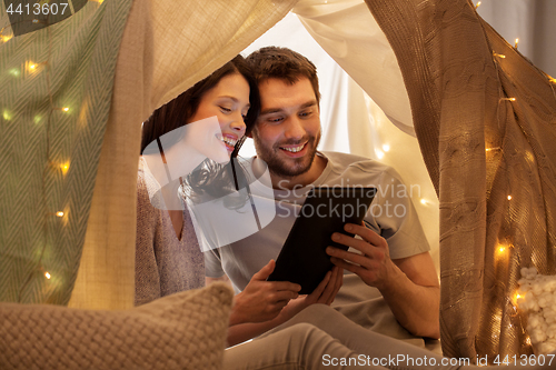 Image of happy couple with tablet pc in kids tent at home