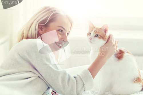 Image of happy young woman with cat in bed at home