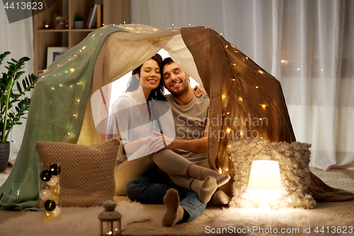 Image of happy couple in kids tent at home