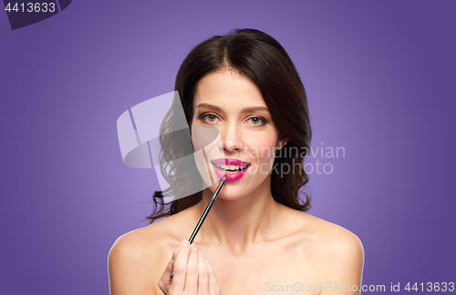 Image of beautiful woman with make up brush for lipstick