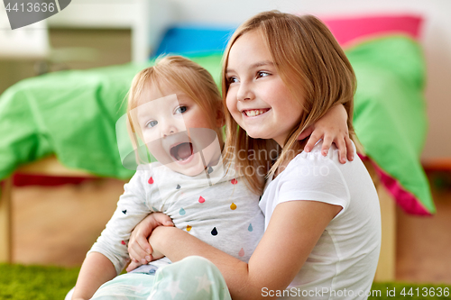 Image of happy little girls or sisters hugging at home