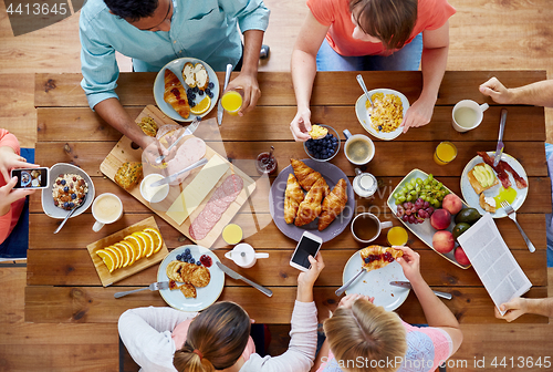 Image of people with smartphones eating food at table