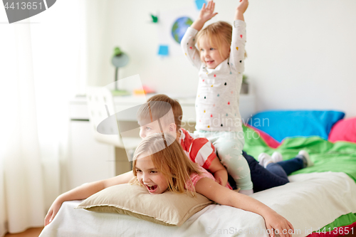 Image of happy little kids having fun in bed at home