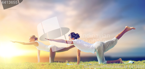 Image of couple making yoga balancing table pose outdoors