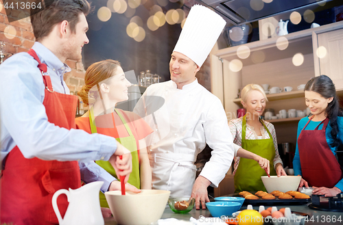 Image of happy friends and chef cook baking in kitchen