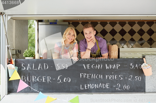 Image of couple of happy young sellers at food truck