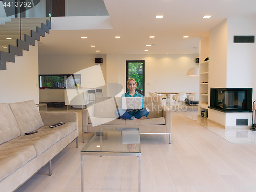 Image of Young woman using laptop at home