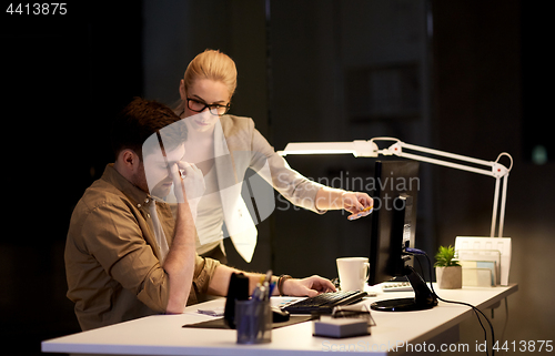 Image of business team with computer working late at office