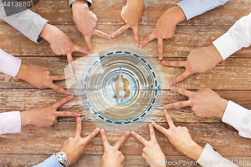 Image of business team showing peace hand sign with bitcoin