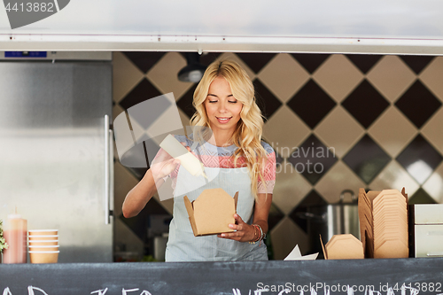 Image of happy saleswoman making wok at food truck