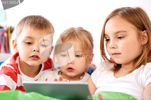 Image of little kids with tablet pc in bed at home