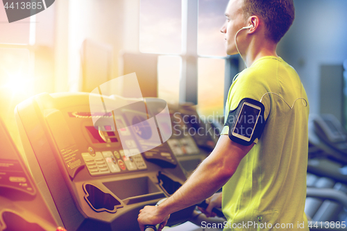 Image of man with smartphone exercising on treadmill in gym