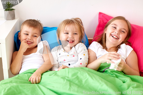 Image of happy little kids having fun in bed at home