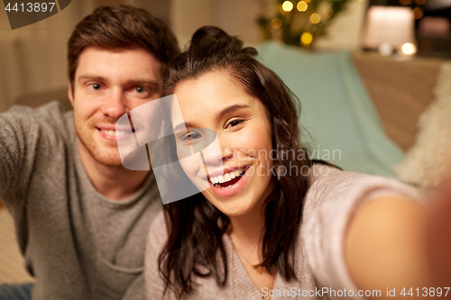Image of happy couple taking selfie at home