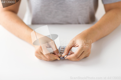 Image of woman hands opening pack of medicine pills