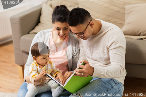 Image of happy family with baby reading book at home