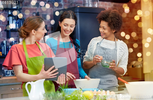 Image of happy women with tablet pc cooking in kitchen