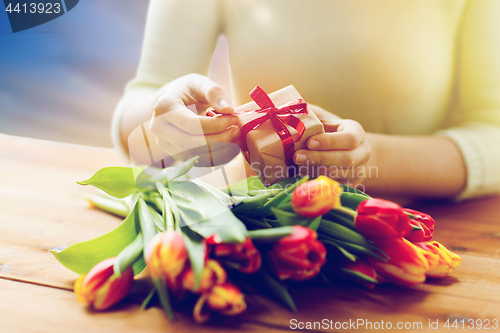 Image of close up of woman with gift box and tulip flowers